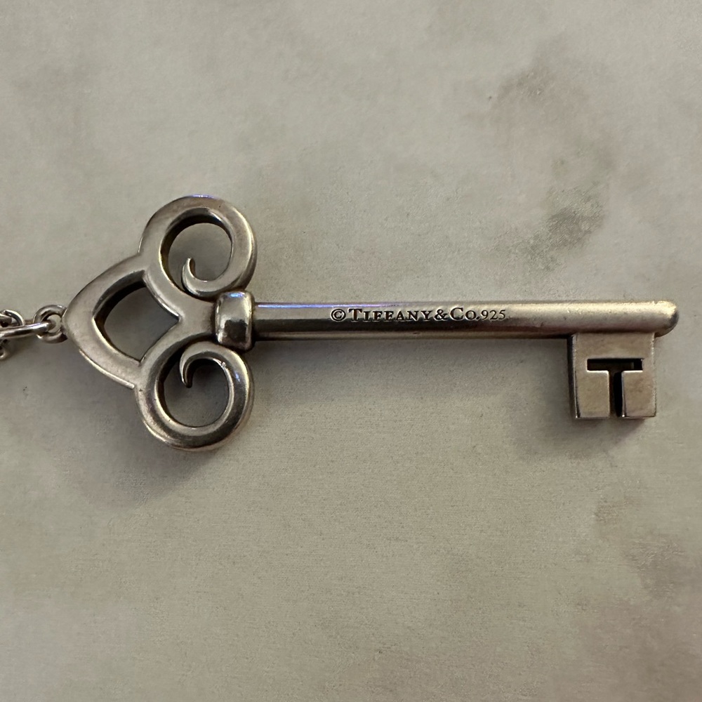 Tiffany & Co SS Fleur De Lis key charm necklace with 16” sterling chain + pouch.